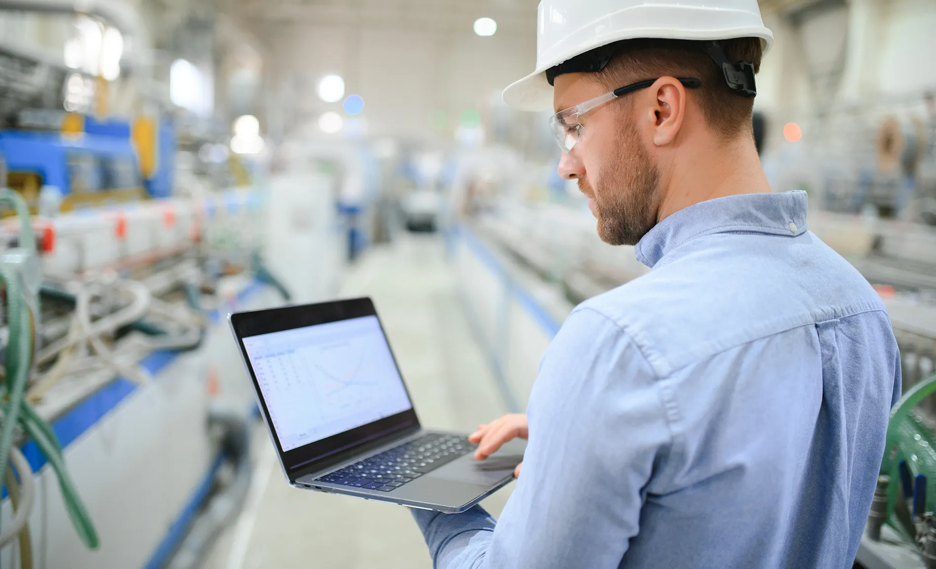 Engineer reviewing Manu Online ERP on a laptop on the factory floor